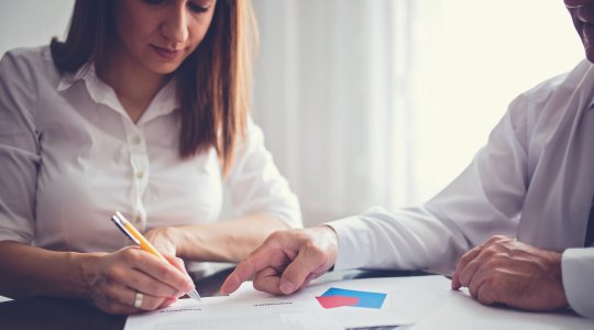 En kvinna undertecknar ett målkontrakt mellan henne som medarbetare och sin chef. | Framfot företagsutbildning