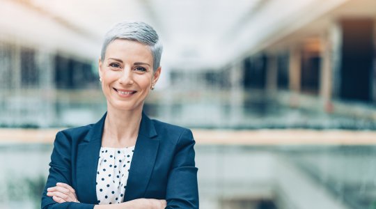 Kvinna med armarna i kors ler mot kameran