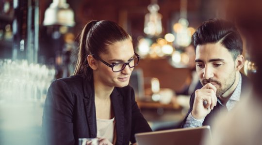 Affärsmänniskor tittar på datorskärm i ett café
