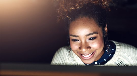 Glad kvinna tittar in i datorskärm